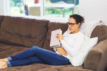 Woman sitting on couch with pelvic pain