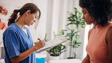 A doctor taking notes while consulting with a patient