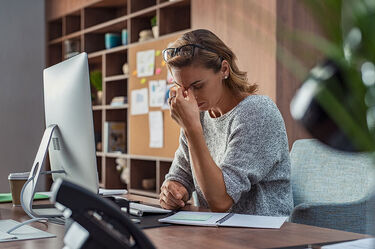 Business woman holding her head when at an office desk