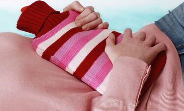 A woman holding a hot water bottle on her stomach