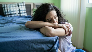 Mature woman sitting end of bed alone